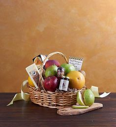 a wicker basket filled with assorted fruit and condiments sitting on a wooden table