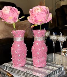 two vases with pink roses in them on a table