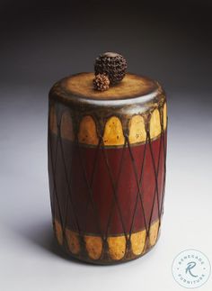 a small drum with a pine cone on top