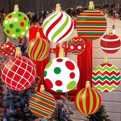 christmas ornaments are hanging from the ceiling in front of a tree with red, green and white balls