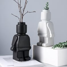 two black and white legos with plants in them on a table next to each other