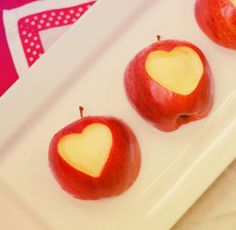 three apples with hearts cut out of them on a plate