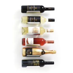 six bottles of wine lined up in a row on a white surface with the top one empty