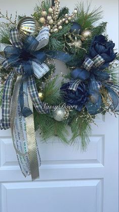 a christmas wreath with blue and gold decorations hanging on a white front door ornament