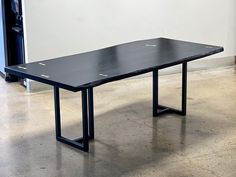 a black table sitting on top of a cement floor next to a white wall in an empty room