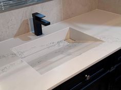 a bathroom sink with a black faucet and marble counter top