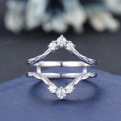 a close up view of a diamond ring on top of a blue cloth with flowers in the background