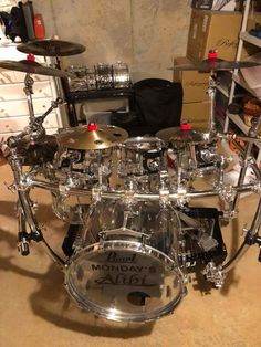 a drum set sitting on top of a floor next to a shelf filled with musical equipment