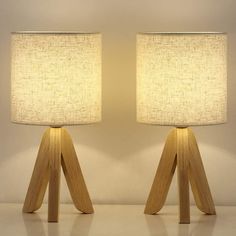 two wooden lamps with white linen shades on them