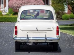 an old white car is parked on the street