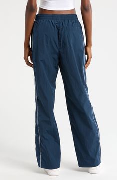 Throwback '70s style and a useful watrer-repellent finish lend style and function to these sporty nylon pants embroidered with a classic Swoosh logo. 30" inseam; 21" leg opening; 13" front rise; 16" back rise (size Medium) Elastic/drawstring waist Side-seam welt pockets; back welt pocket Water repellent 100% nylon Machine wash, tumble dry Imported Nike Stretch Nylon Bottoms, Functional Wide Leg Nylon Parachute Pants, Athleisure Nylon Parachute Pants, Nike Blue Nylon Bottoms, Nylon Wide Leg Parachute Pants For Sports, Wide Leg Nylon Parachute Pants For Sports, Nylon Straight Leg Athleisure Pants, Nike Nylon Parachute Pants With Pockets, Nike Nylon Long Pants