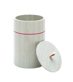 a white cup with a pink stripe on the side and a wooden lid next to it