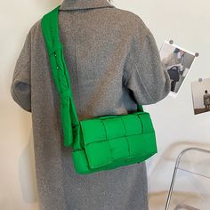 the back of a woman's green purse on display at a fashion store,