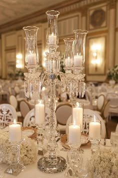 an elegant centerpiece with candles and flowers on a table in a banquet hall or wedding reception