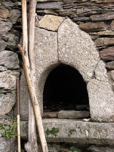 there is a stone oven built into the side of a rock wall with logs sticking out of it