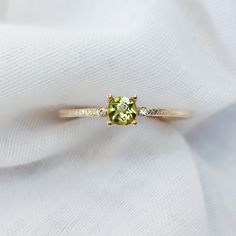 "Solid Gold Peridot Ring With Diamond/ Peridot Engagement Ring/ Promise Ring For Women/ August Birthstone Ring, Textured Round Peridot Ring  Beautiful 9K gold textured band, peridot and diamond engagement ring. The ring features a round 4mm peridot set in a 4 claw prong setting.  Materials: Solid 9ct yellow gold Gemstone: 4mm Peridot Band Width:  1.2mm  Photos of this ring have been taken close up for detail. Please refer to a ruler for dimensions of stone and band width. Don't forget to hit \"favourite\" on the right, so it remains in your favourites list and/ or add to your wish list(s). ------------------------------------------------------------------------------------------------------------------------------------------ Want to find out more? check out our shop https://www.etsy.com/u Diamond And Peridot Ring, Peridot Diamond Ring, Yellow Gold Rings With Yellow Sapphire And Accent Stones, Peridot Ring With Prong Setting In Round Cut, Anniversary Peridot Diamond Ring, Peridot Diamond Ring With Gemstone For Anniversary, Peridot Birthstone Diamond Ring Fine Jewelry, Wedding Rings With Peridot Gemstone Accents, Peridot Diamond Ring For May Birthstone