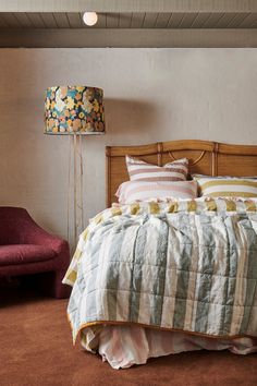 a bed sitting next to a red chair in a bedroom on top of a carpeted floor