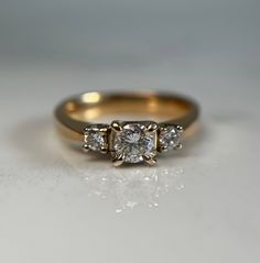 three stone diamond ring on white surface with reflection