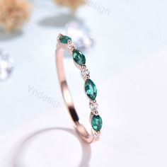 an image of a ring with emeralds and diamonds on the table in front of it