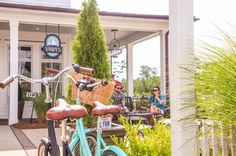 two people sitting at a table with bikes in front of a building that has a sign on it