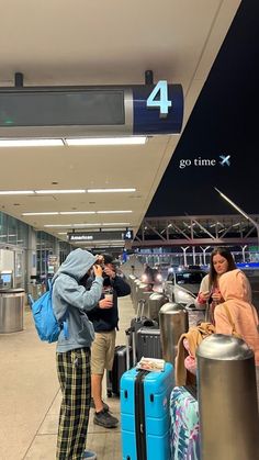 two people standing next to each other at an airport with luggage and bags in front of them