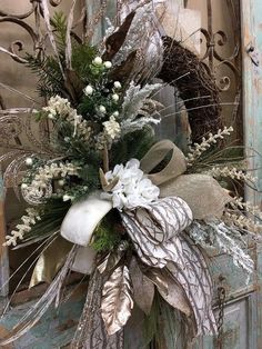 a wreath with white flowers and greenery on an old door