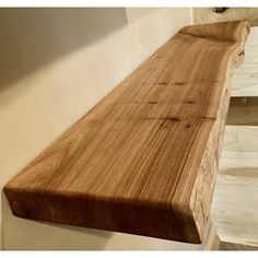 a wooden bench sitting on top of a white wall next to a window sill