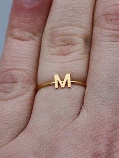 This elegant gold initial ring is perfect for stacking, making it a great gift for any occasion - whether a mother's day surprise or a best friend's birthday present. Crafted from quality stainless steel, this letter ring will look beautiful for years to come. Featuring a letter of your choosing, this ring can be worn alone or stacked making it perfect for gifting to friends or family. The subtle, yet sweet letter ring looks elegant alone or as part of a larger stack. This gold letter ring is th Dainty Gold Stackable Rings With Initials, Simple Gold Initial Ring For Anniversary, Everyday Gold Monogram Initial Ring, Gold Monogram Initial Ring For Everyday, Gold Monogram Initial Ring For Everyday Wear, Gold Stainless Steel Stackable Rings For Gift, Minimalist Initial Rose Gold Ring, Gold Minimalist Personalized Initial Ring, Personalized Gold Initial Ring Minimalist Style