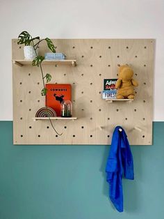 a wall mounted shelf with two shelves holding books and a stuffed animal next to it