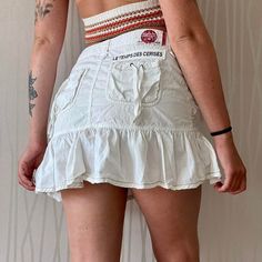 The adorable cargo miniskirt from brand Les Temps Des Cerises in the late 90's / early 2000's! Such a cute and flirty summer staple with the best detailing!  Features midweight 100% cotton construction, mid- low waist fit, drop waist affect, ruffle hem detail, tie up details on the front and back pockets, brand patch on the back waist band and above the pocket, white colorway and mini length! Tagged size 27, fits like a medium This piece has very light general wear and tear Y2k Style Fitted Skort With Ruffles, Y2k Fitted Skort With Ruffles, Y2k Style Ruffled Skort, Y2k Fitted Ruffled Skort, Y2k Fitted Ruffle Skort, Y2k Style Cotton Mini Skirt, Y2k Style Mini Cotton Skirt, Y2k Style Mini Skirt With Ruffles, Y2k Mini Cotton Skort