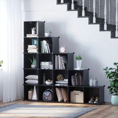 an open bookcase sitting in front of a stair case next to a potted plant