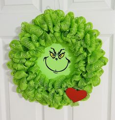 a green wreath with the grin face drawn on it and a red heart hanging from the front door