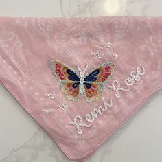 a pink bandana with a butterfly embroidered on it