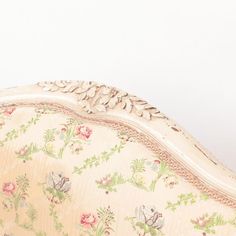 an ornately decorated couch against a plain white wall with flowers and leaves on it