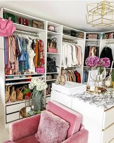 a pink chair sitting in front of a closet filled with clothes and handbags