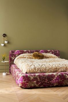 a bed sitting on top of a wooden floor next to a wall