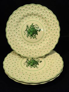 two green and white plates stacked on top of each other, with small dots around them