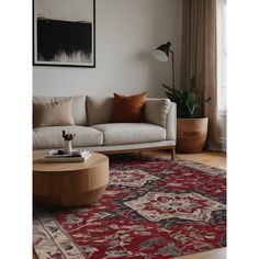 a living room with a couch, coffee table and rug in front of a window