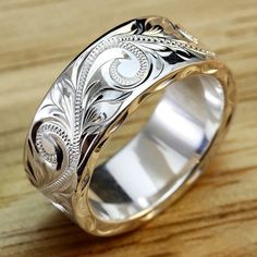 a wedding ring with an intricate design on it's center and sides, sitting on top of a wooden table