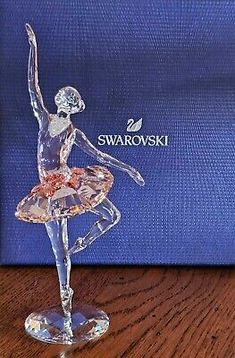 a glass figurine of a ballerina on top of a wooden table in front of a blue box