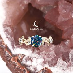 a blue diamond ring sitting on top of a rock