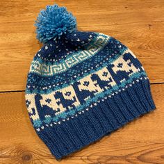 a blue and white knitted hat with a pom - pom