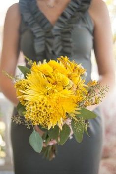 a woman holding a bouquet of yellow flowers