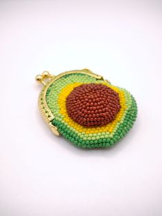 a green, yellow and red beaded coin purse on a white surface with a gold chain