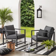 two chairs sitting on top of a black and white striped rug next to a potted plant