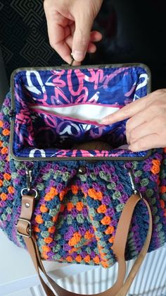 a woman is holding a crocheted purse with her hand on the handle and it's zipper open