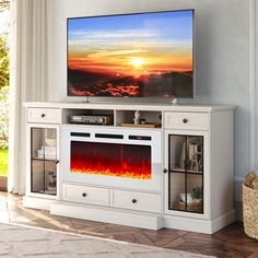 a flat screen tv sitting on top of a white entertainment center next to a window