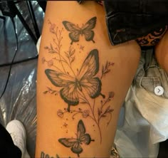 a woman's thigh with butterflies and flowers on it