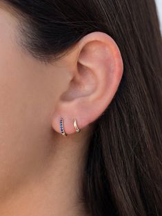 a woman's ear is shown with two small blue stones in the middle of it