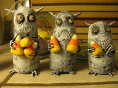 three cement owls holding candy cornucons on a table